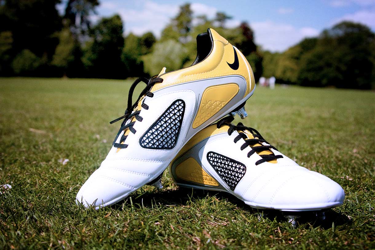 Chaussures de foot propres, blanches et jaunes posées sur un terrain